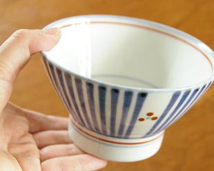 砥部焼・梅山窯 とくさみつ紋の茶碗を手に持って