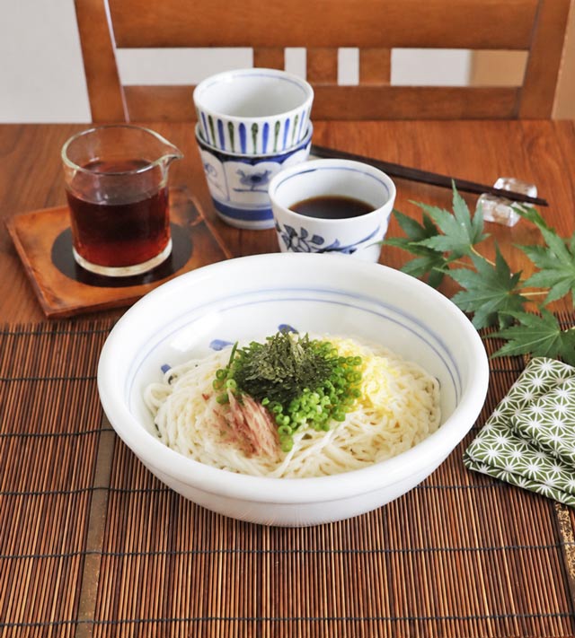風船花の玉ぶち鉢に数人分のがめ煮をたっぷり盛り付けた食卓の風景