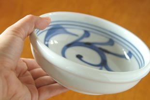 砥部焼・梅山窯 内からくさの半玉ぶち鉢を手に持って