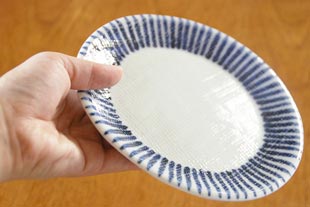 砥部焼・梅山窯 とくさ柄の布目丸皿を手に持って