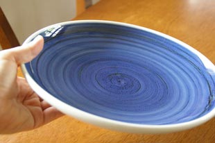 砥部焼・梅山窯 藍色の大皿(8寸)を手に持って