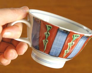 砥部焼・梅山窯 色絵模様のコーヒーカップを手に持って