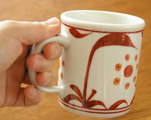 砥部焼・梅山窯 赤太陽のマグカップを手に持って