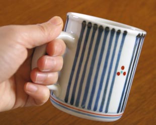 砥部焼・梅山窯 とくさみつ紋の切立マグカップを手に持って