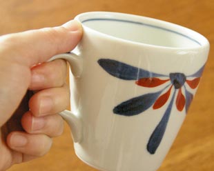 砥部焼・梅山窯　花もようのモーニングカップを手に持って