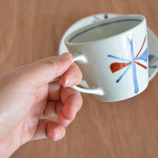 砥部焼・梅山窯 赤蝶文のコーヒーカップを手に持って