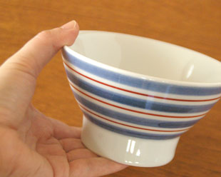 砥部焼・梅山窯 あい赤の茶碗(大)を手に持って