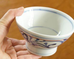 砥部焼・梅山窯 赤線からくさの茶碗(小)を手に持って