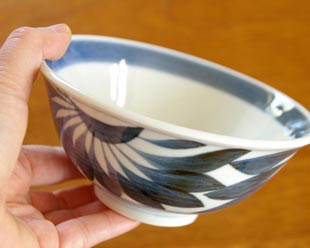砥部焼・梅山窯 菊もようの反茶碗を手に持って