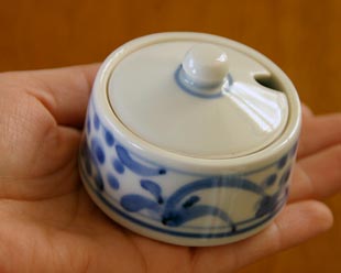砥部焼・梅山窯 太陽柄の薬味入れを手に持って