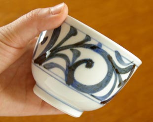 砥部焼・梅山窯　からくさの湯呑を手に持って