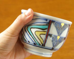 砥部焼・西岡工房 いろえ金彩の湯呑を手に持って