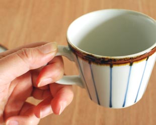 砥部焼・千山窯 縁紅のコーヒーカップを手に持って