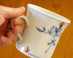砥部焼・陶房遊 花ちらしのマグカップを手に持って