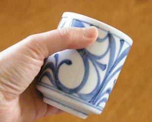 砥部焼・梅山窯 からくさの筒湯呑を手に持って